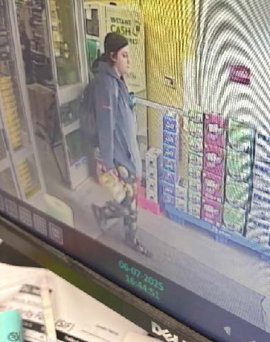 A person with a black hat and blue sweatshirt leaving a business.